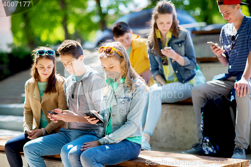 Image of teenage friends with smartphones outdoors