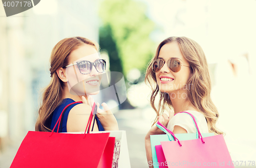 Image of happy young women with shopping bags in city