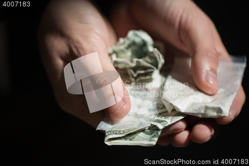 Image of close up of addict hands with drugs and money