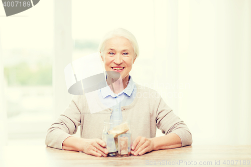 Image of senior woman with money in glass jar at home