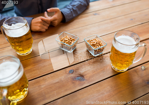 Image of close up of hands with beer mugs at bar or pub