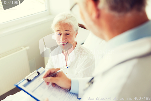 Image of senior woman and doctor with clipboard at hospital