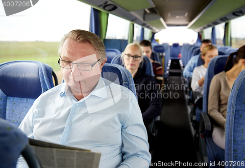 Image of happy senior man reading newspaper in travel bus