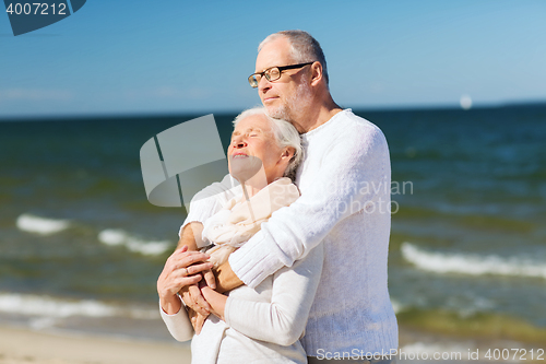 Image of happy senior couple hugging on summer beach