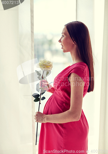 Image of happy pregnant woman with rose flower at home