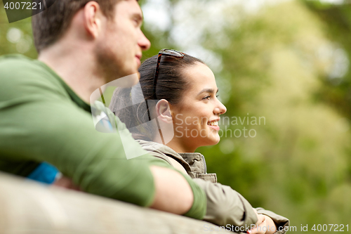 Image of smiling couple with backpacks on bridge in nature