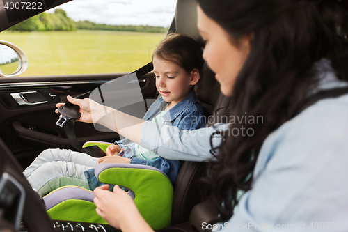 Image of happy woman fastening child with seat belt in car