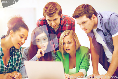 Image of international students looking at laptop at school