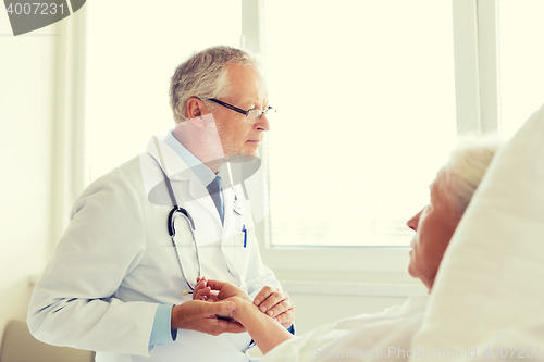 Image of doctor checking senior woman pulse at hospital