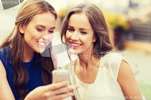 Image of happy young women with smartphone at outdoor cafe