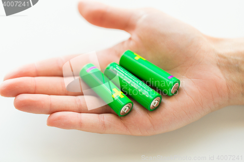 Image of close up of hand holding green alkaline batteries