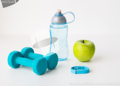 Image of dumbbells, fitness tracker, apple and bottle