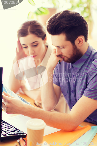 Image of creative team with reading paper in office