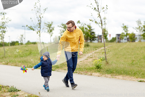 Image of happy father and son with pinwheel toy outdoors