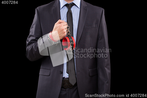 Image of man in a business suit with leather bound. handcuffs. sex Toys