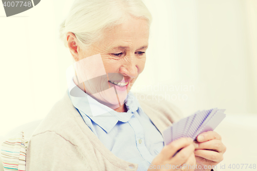 Image of happy senior woman playing cards at home