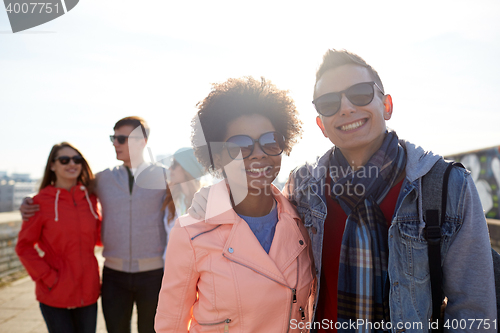 Image of happy teenage friends in shades hugging on street