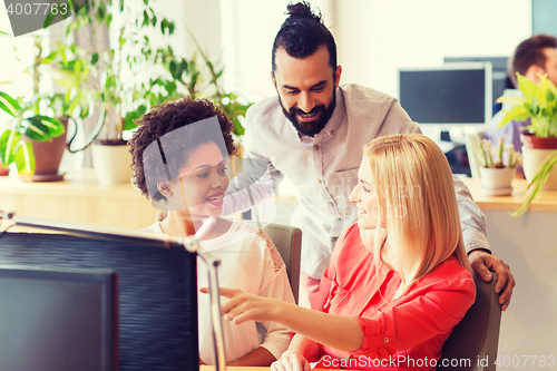 Image of happy creative team with computer in office