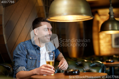 Image of happy man drinking draft beer at bar or pub