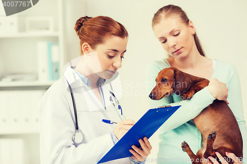 Image of woman with dog and doctor at vet clinic