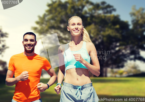 Image of smiling couple running over summer park background