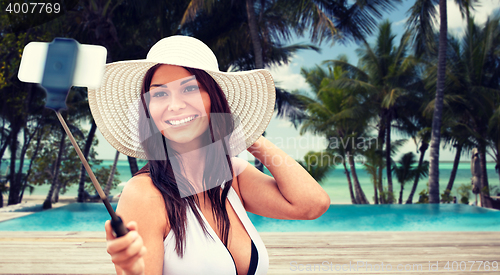 Image of smiling young woman taking selfie with smartphone