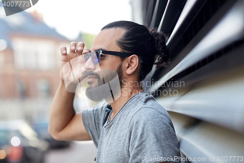 Image of happy man with beard and sunglasses on city street