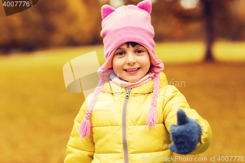 Image of happy little girl showing thumbs up outdoors
