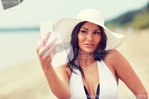 Image of young woman taking selfie with smartphone