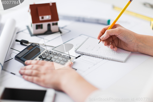 Image of close up of hand on blueprint writing to notebook