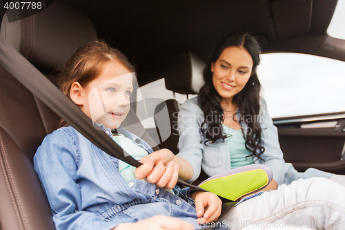 Image of happy woman fastening child with seat belt in car