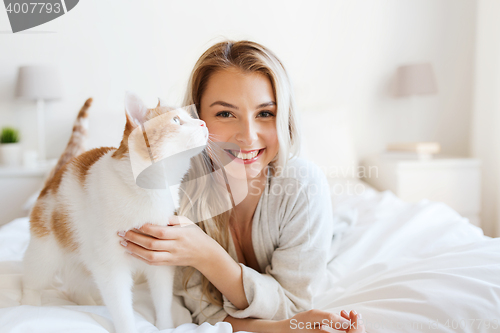 Image of happy young woman with cat in bed at home