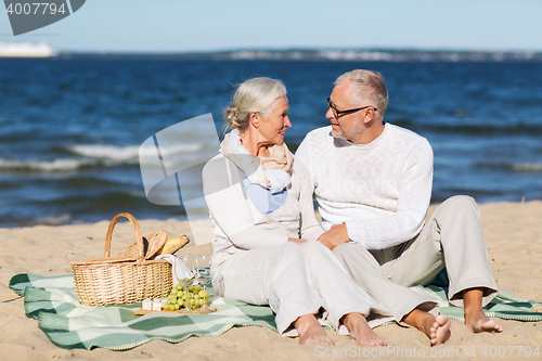 Image of happy senior couple having picnic on summer beach