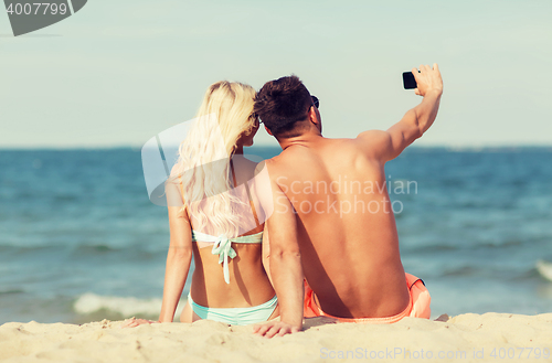 Image of happy couple in swimwear sitting on summer beach