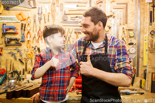 Image of father and little son making thumbs up at workshop