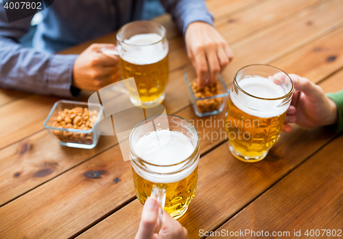 Image of close up of hands with beer mugs at bar or pub