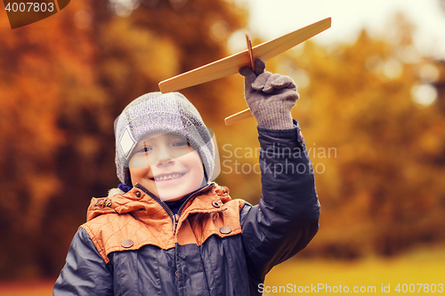 Image of happy little boy playing with toy plane outdoors