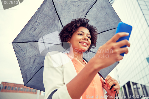 Image of businesswoman with umbrella texting on smartphone