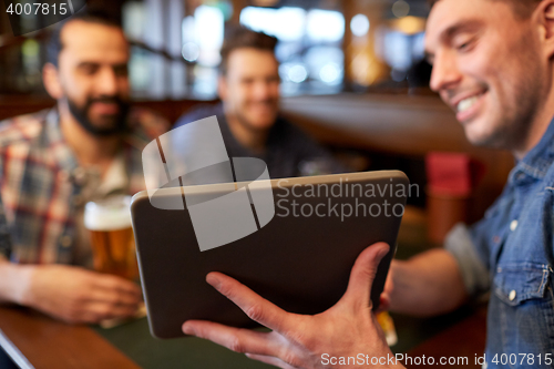 Image of male friends with tablet pc drinking beer at bar