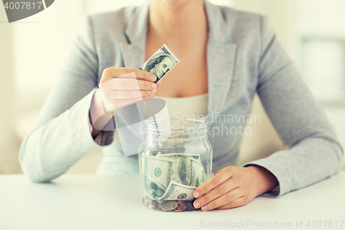 Image of close up of woman hands and dollar money in jar