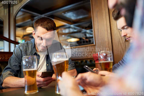 Image of men with smartphones drinking beer at bar or pub