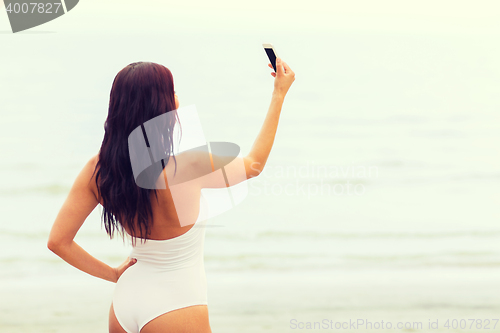 Image of young woman taking selfie with smartphone