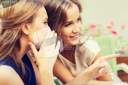 Image of smiling young women gossiping at outdoor cafe