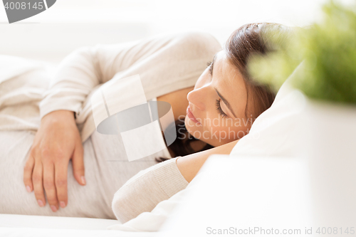 Image of happy pregnant woman lying on bed at home