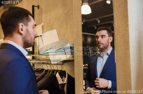 Image of man trying jacket on at mirror in clothing store