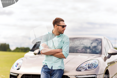 Image of happy man standing at car outdoors