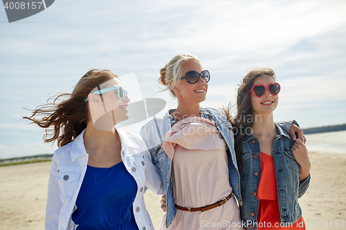 Image of group of smiling women in sunglasses on beach