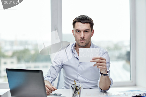 Image of businessman showing blank paper card at office