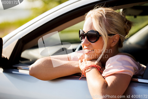 Image of happy teenage girl or young woman in car
