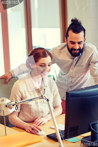 Image of happy creative team with computer in office